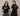 Two people wearing Trans Joy is Sacred black scoop neck t-shirts